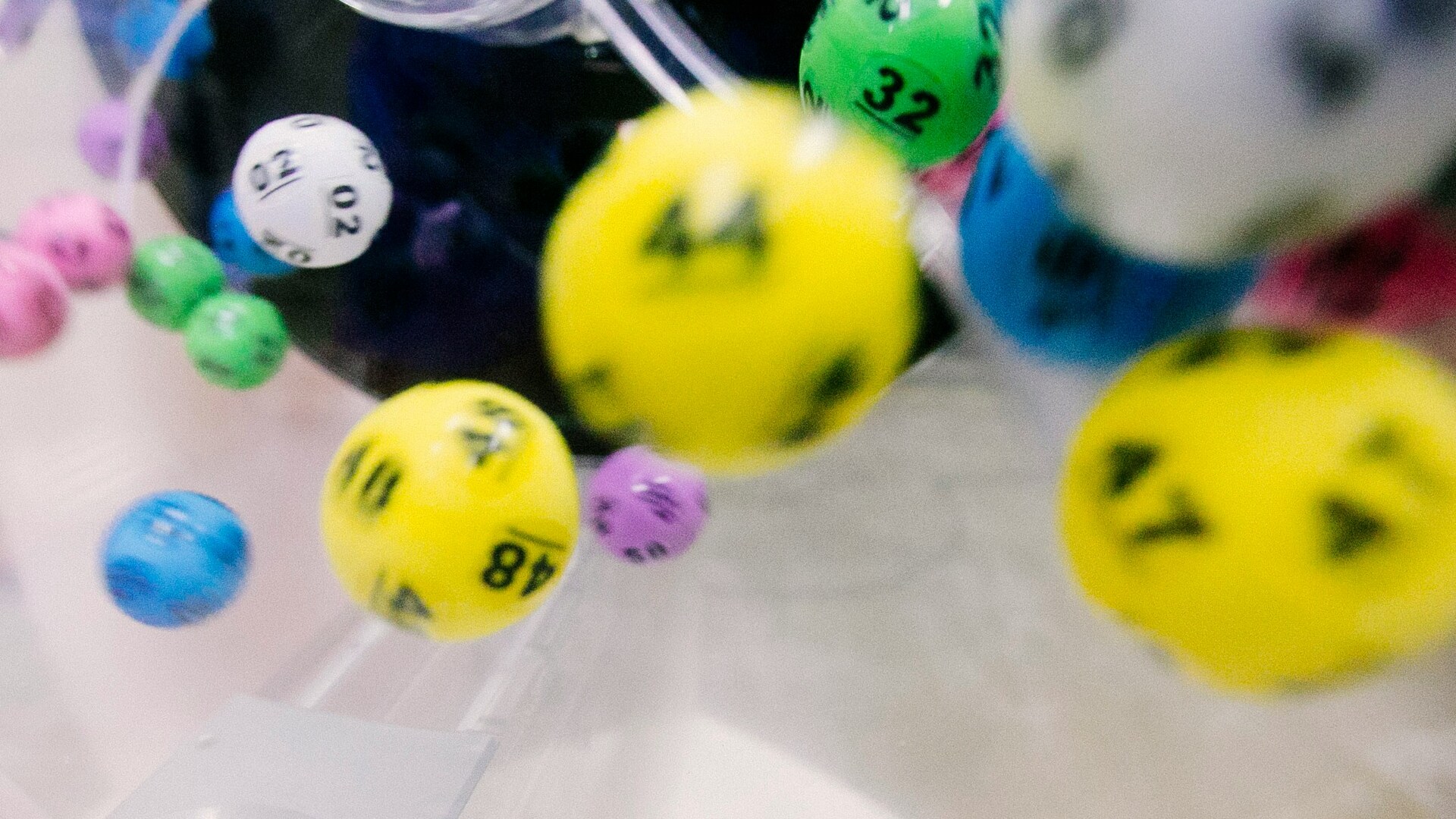 Photo en gros plan de boules de loto colorées avec des numéros, en mouvement dans une machine de tirage.