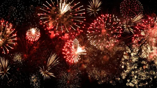 Une multitude d'explosions de feux d'artifice &eacute;clatants dans les tons rouge, blanc et dor&eacute;, remplissant un ciel nocturne noir de lumi&egrave;re et d'&eacute;tincelles.